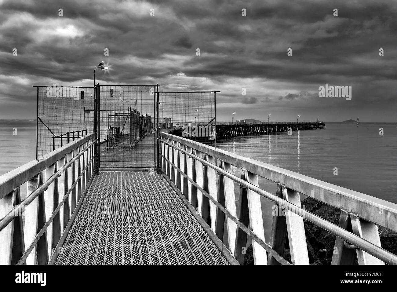 Ingresso alla lunga piegato pontile in legno in Esperance città e la baia durante la pioggia e la tempesta al tramonto. Foto Stock
