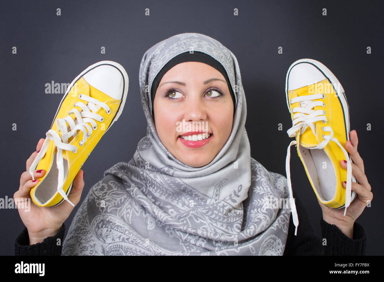 Bella donna musulmana holding sneakers giallo Foto Stock