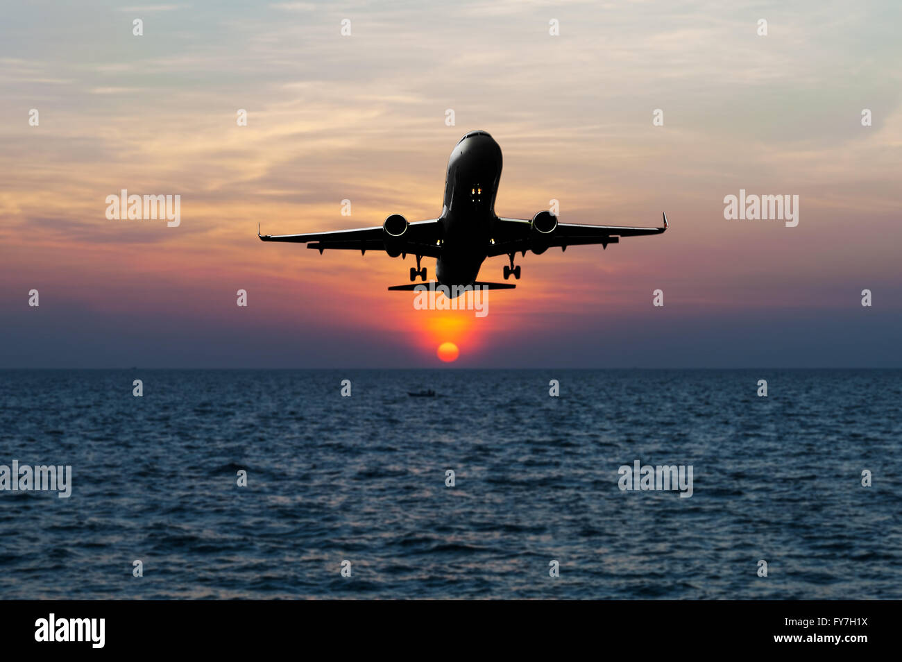 Aeroplano scendono verso il paese sul mare sfocata tramonto nel crepuscolo Foto Stock