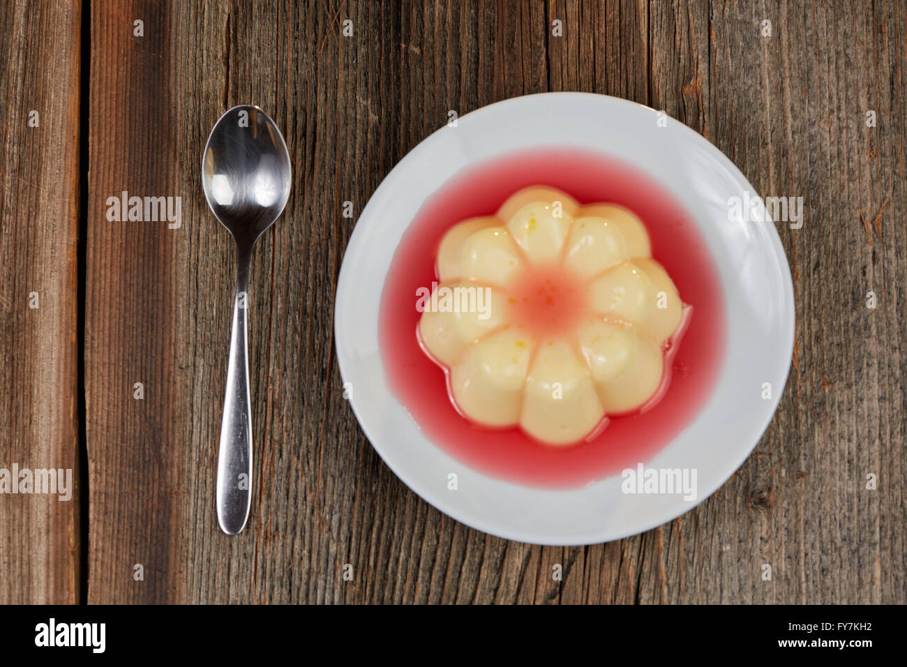 Giallo budino alla vaniglia con salsa di fragole su rown tavolo in legno Foto Stock