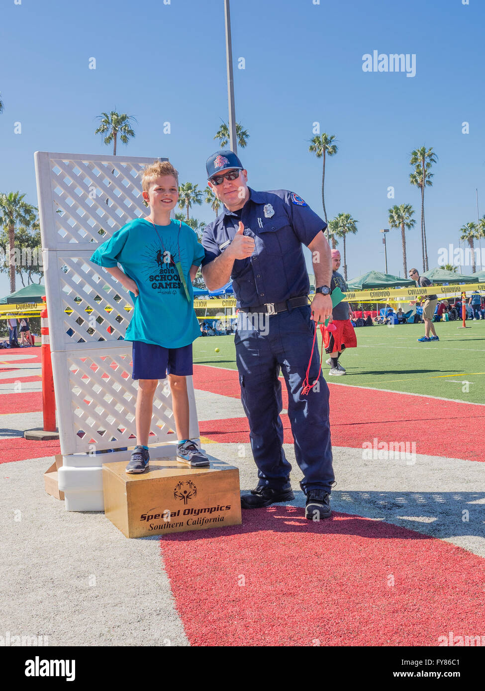 Un disabile giovane ragazzo 10-12 riceve il suo premio da un vigile del fuoco in uniforme per competere nel sud della California Special Olympics Foto Stock