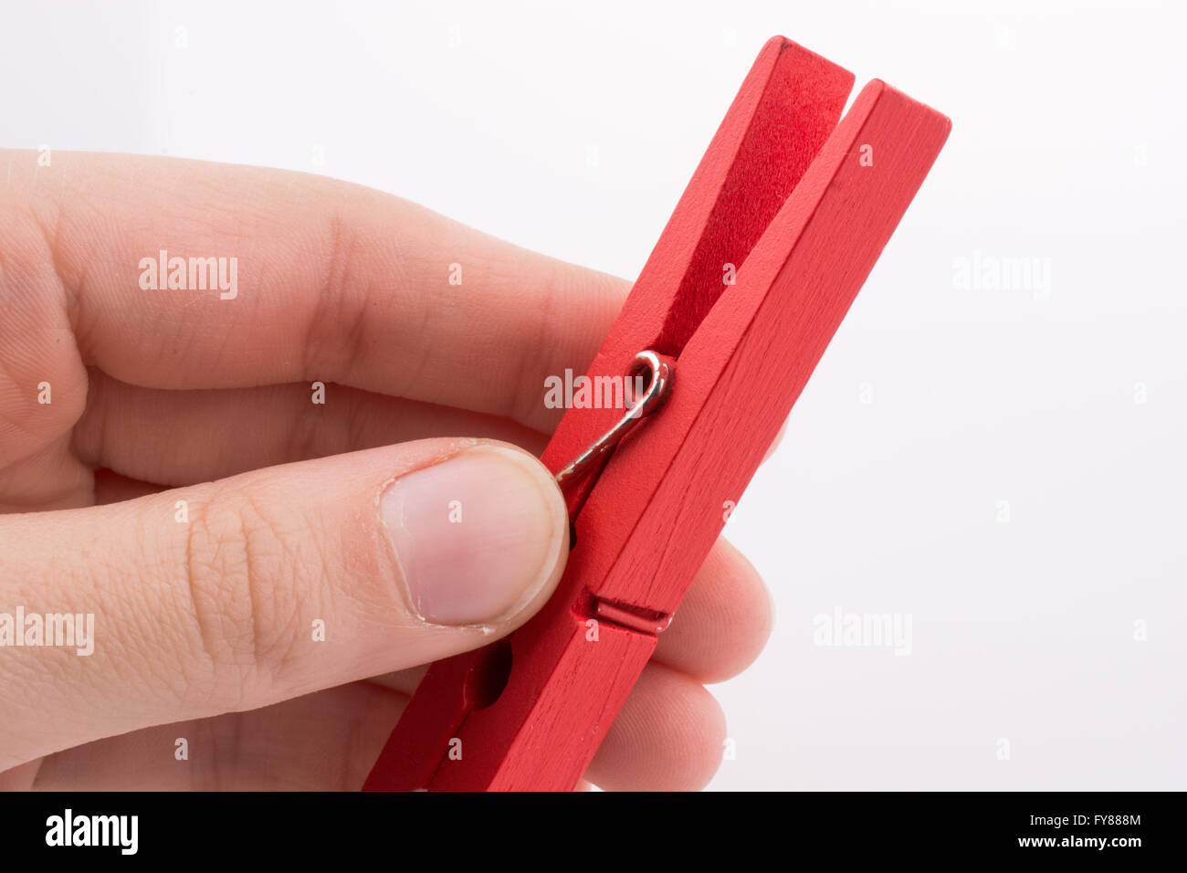 Mano che tiene un clothespin rosso su sfondo bianco Foto Stock