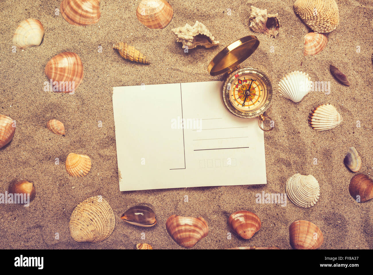 Cartolina vuota nella calda sabbia spiaggia e bussola magnetica con alcune conchiglie di mare, copia spazio per vacanze estate vacanza messaggio, top Foto Stock