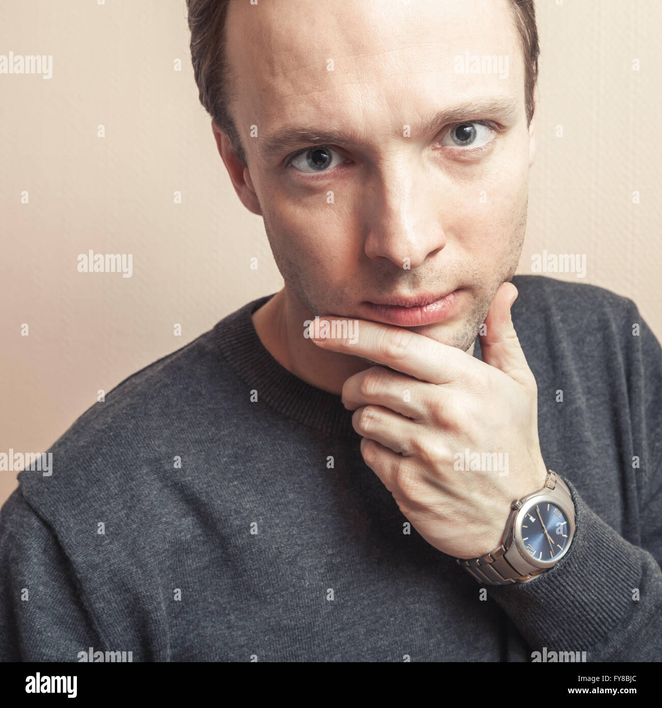 I giovani a pensare bello uomo caucasico, ritratto in studio oltre il muro grigio Sfondo, vecchio stile filtro foto, la correzione delle tonalità Foto Stock