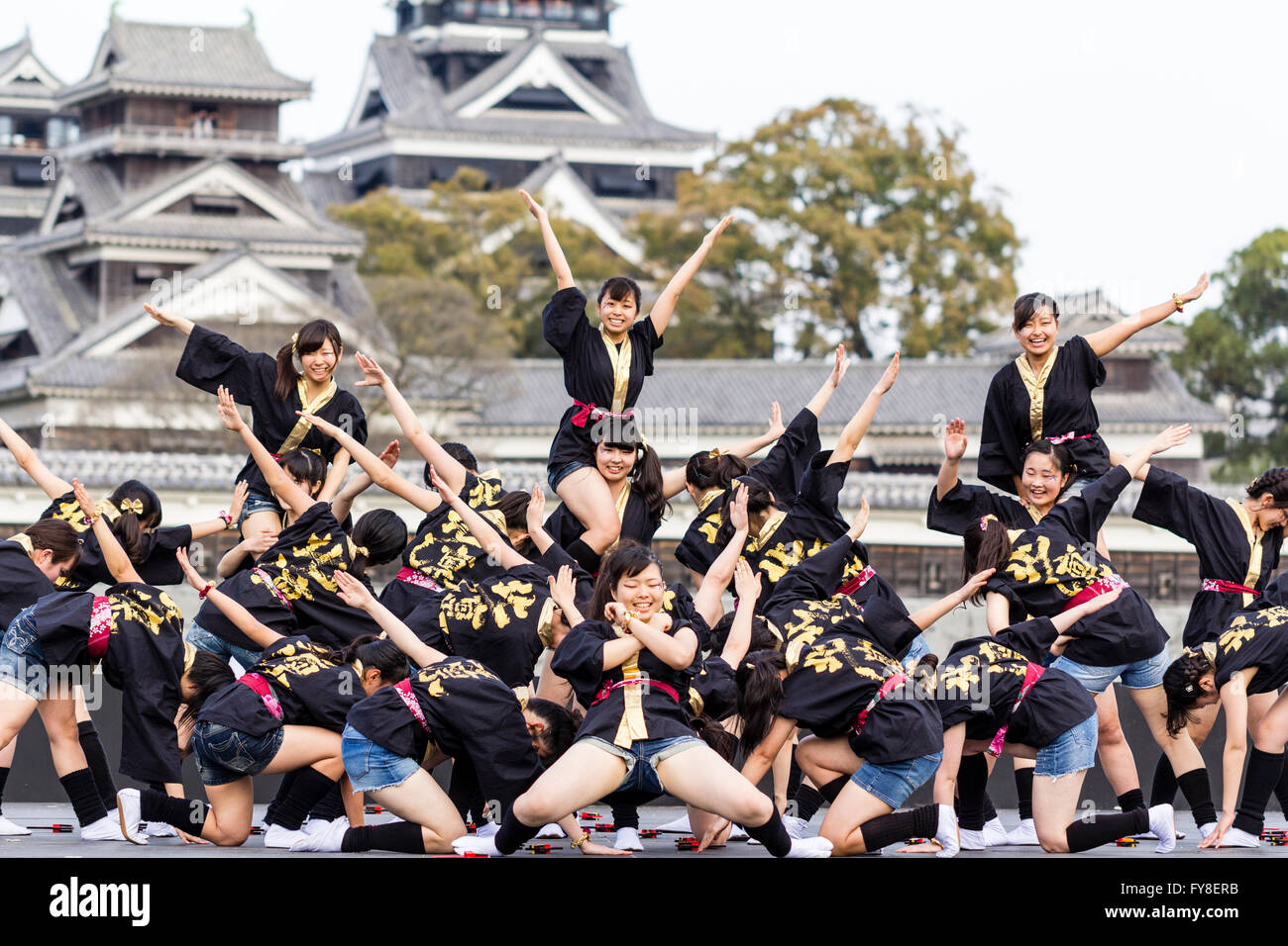 Femmina giapponese dance troupe di ragazze adolescenti, ballando sul palco all'aperto con castello di Kumamoto dietro di loro, durante l'annuale festival Yosakoi. Foto Stock
