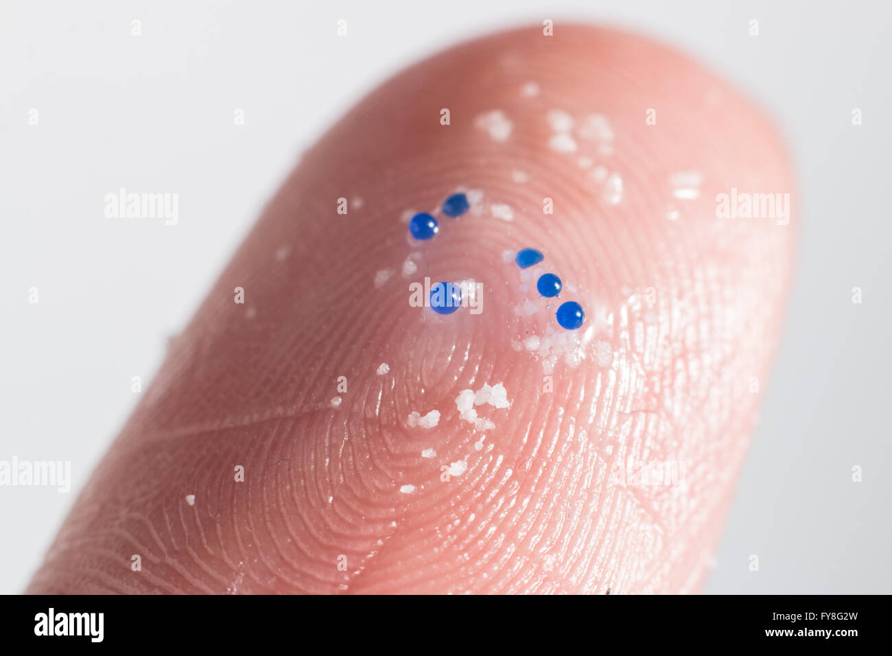 Close up di plastica micro perline sulla punta di un dito Foto Stock