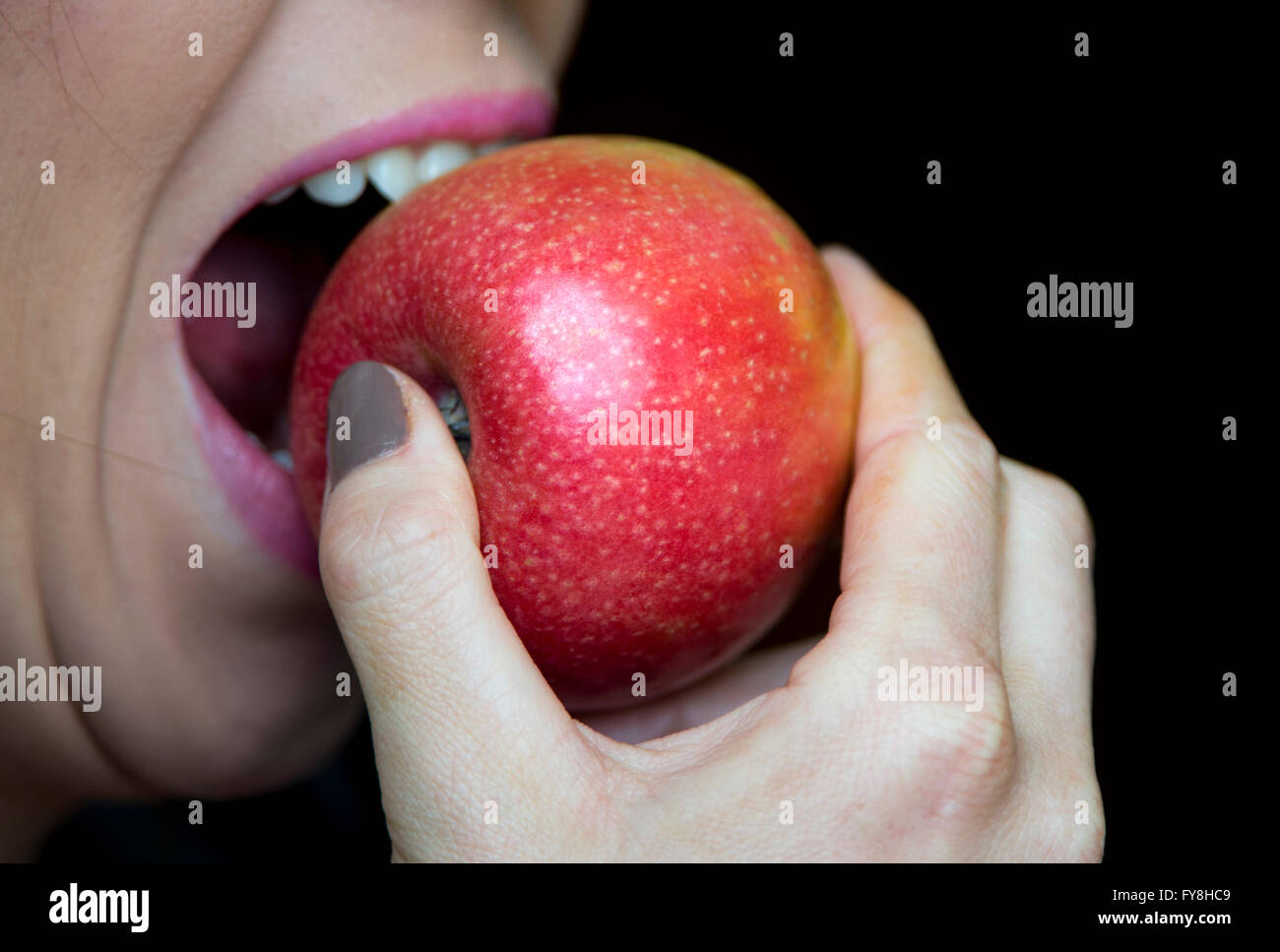 Una donna di mordere in un Apple Foto Stock