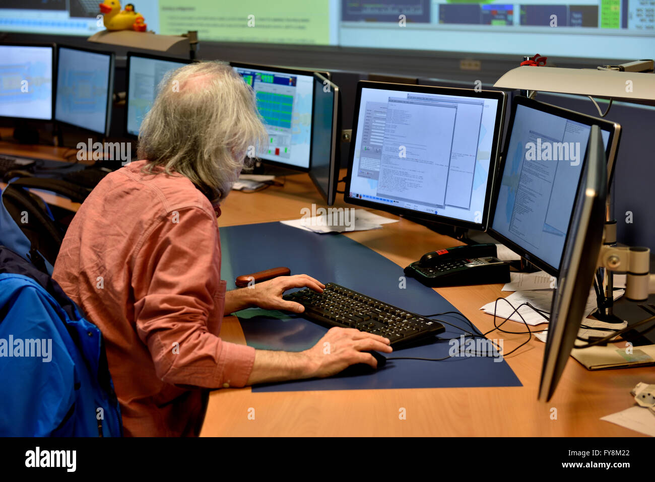 Fisico presso i monitor dei computer in sala di controllo del rivelatore ATLAS al CERN. Foto Stock