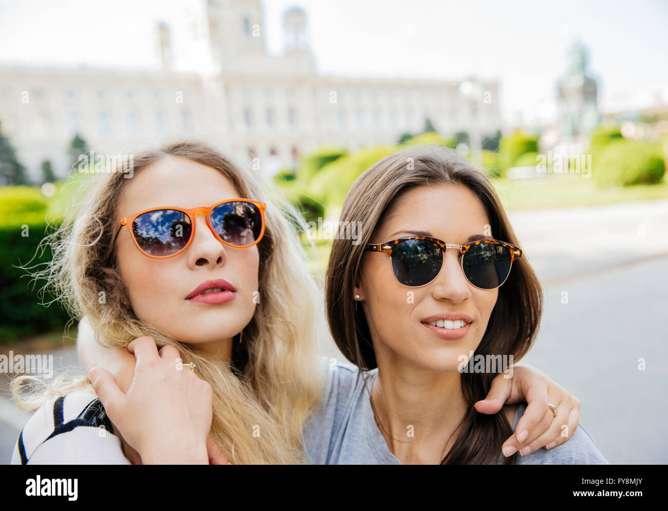 Austria, Vienna, due giovani donne abbracciando con il Museo di Storia dell'arte in background Foto Stock