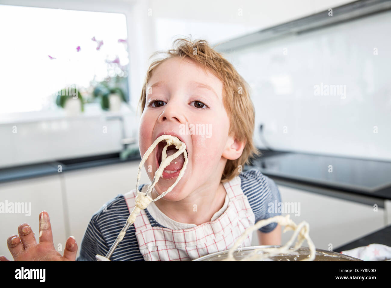 Ragazzo leccare pasta mixer off Foto Stock