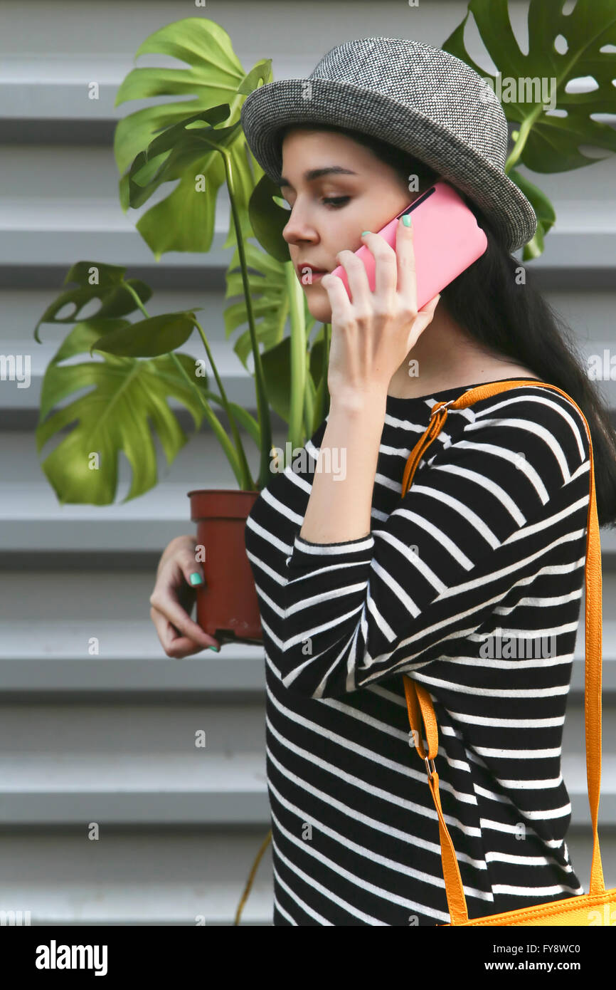 Donna di telefonare con lo smartphone che porta una Monstera deliciosa Foto Stock