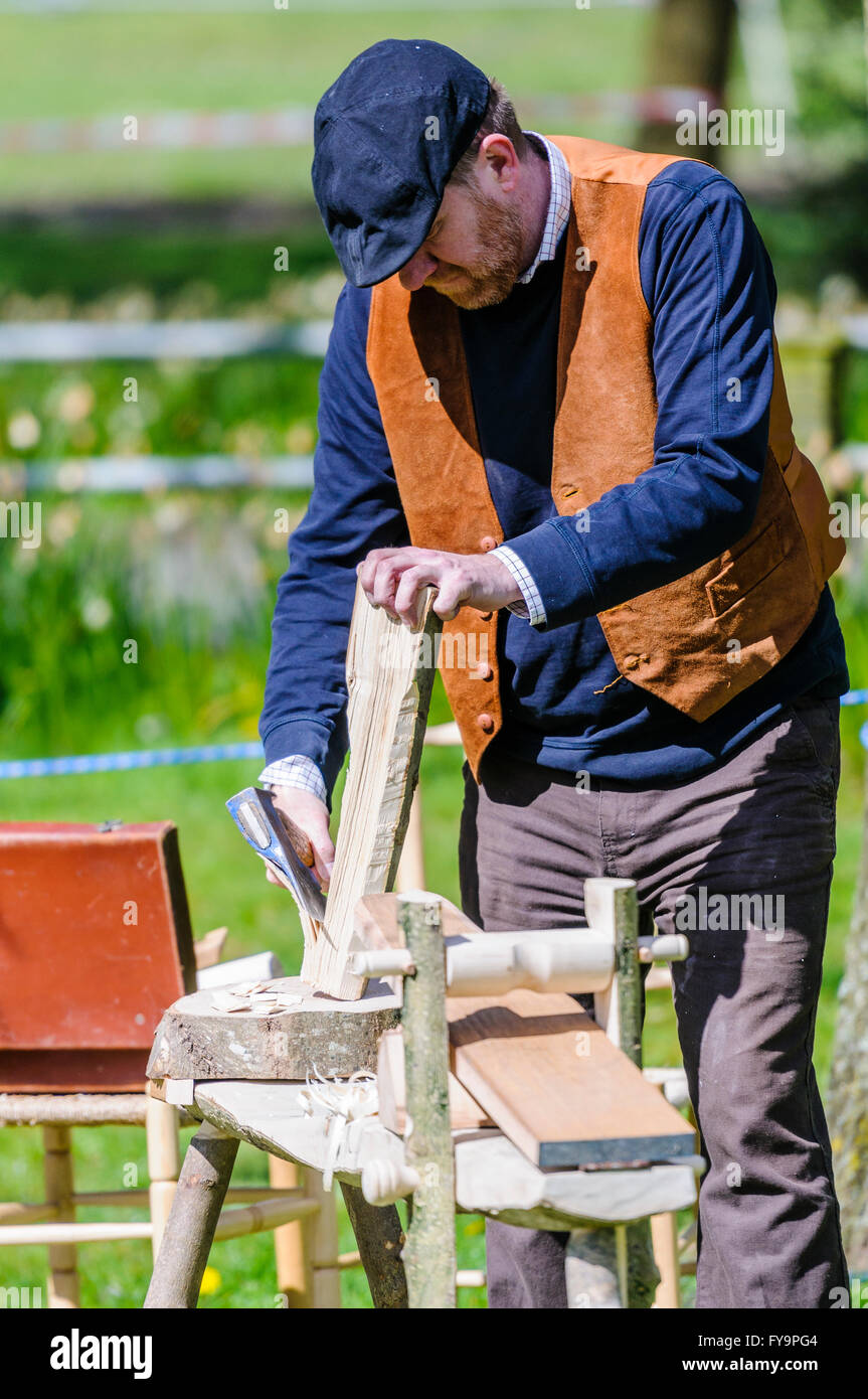 Un artigiano del legno utilizza una mano ax per circa attorno a un pezzo di legno. Foto Stock