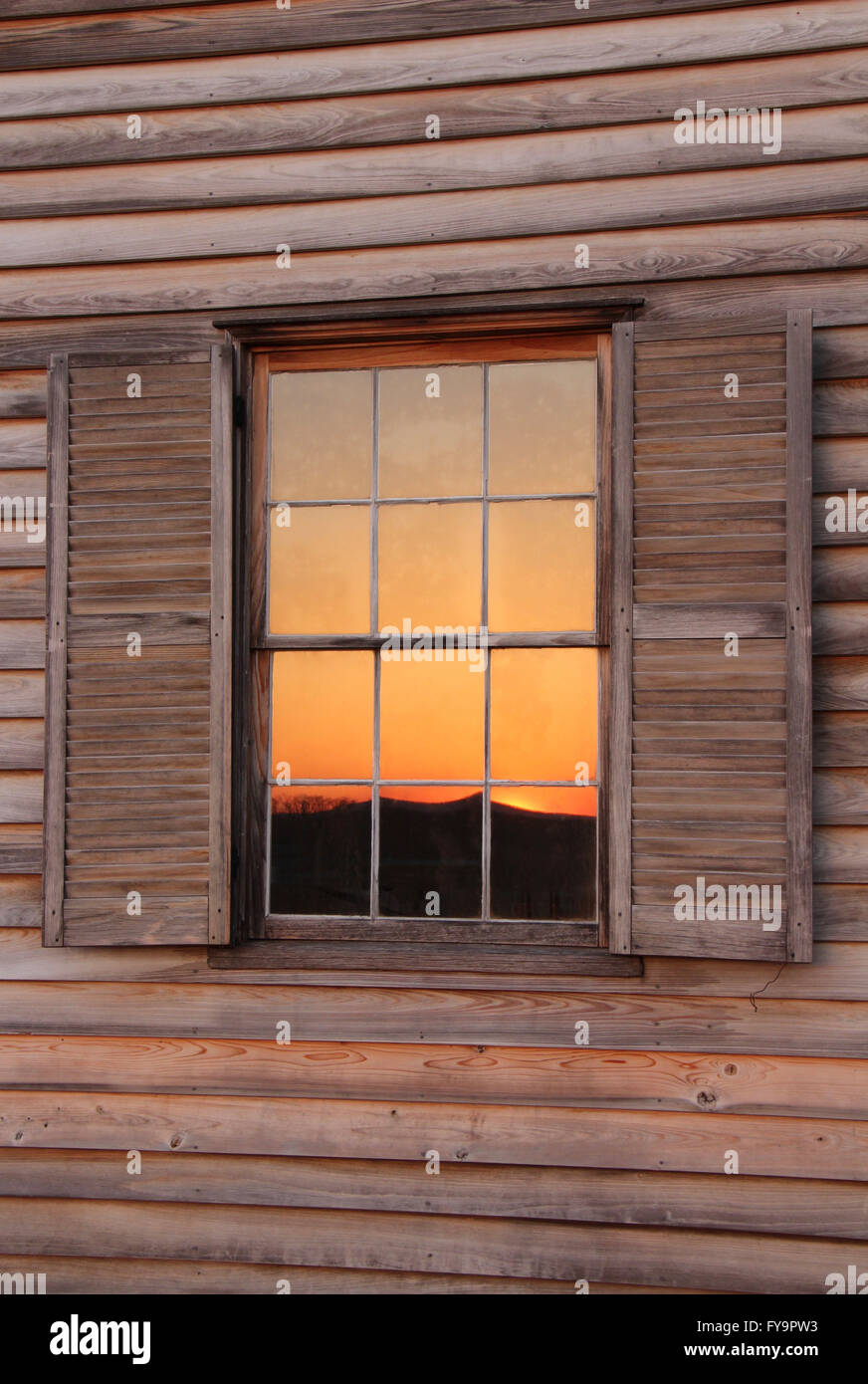 Tramonto riflesso nella finestra di casa in legno Foto Stock