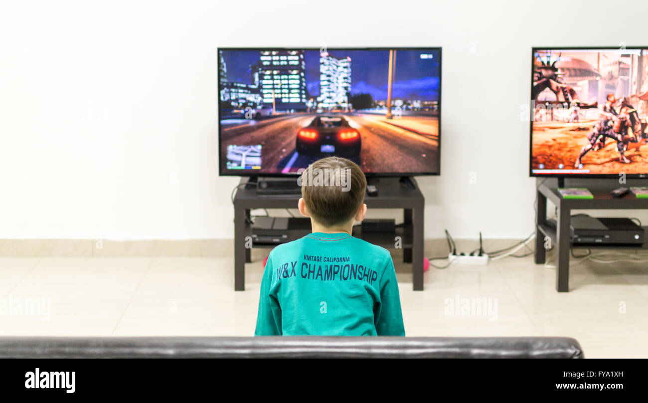 Bambino riproduce un video gioco mentre sua madre negozi in Reifka, Russia il 7 marzo 2016 Foto Stock