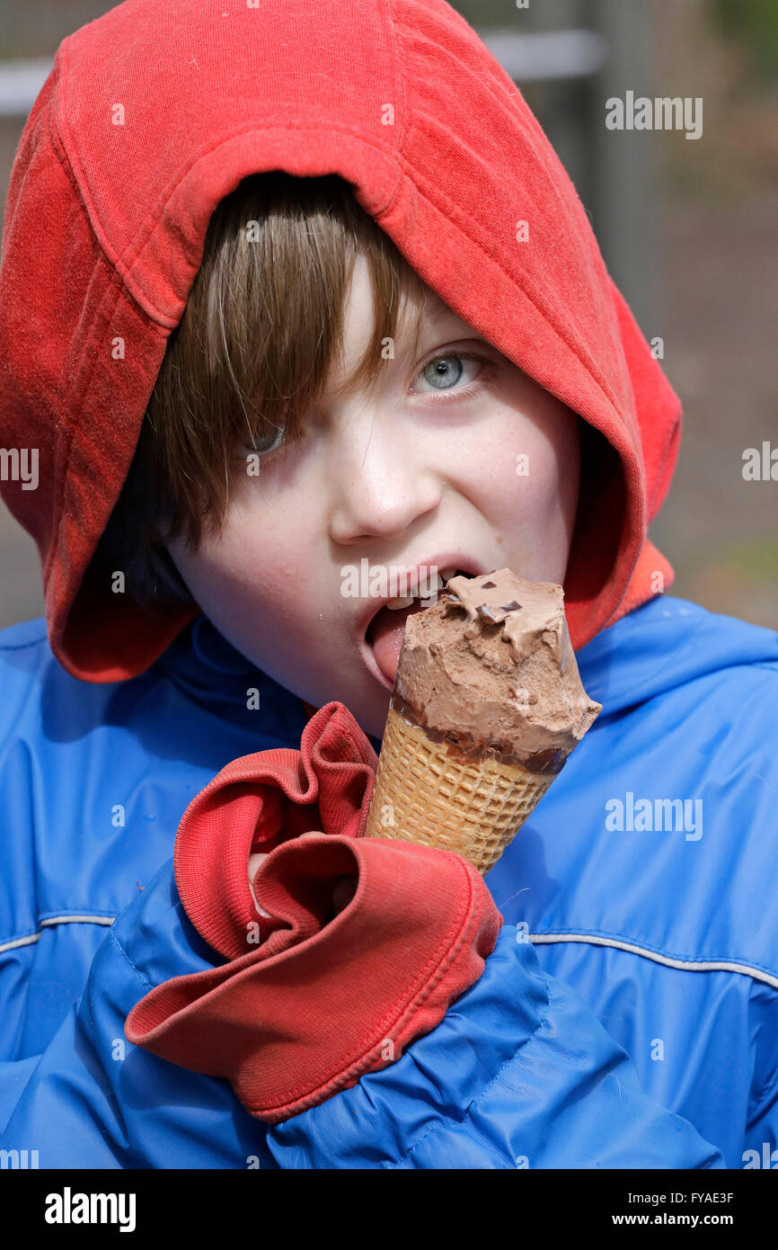 Ragazzo la sensazione di freddo e a mangiare il gelato tuttavia Foto Stock