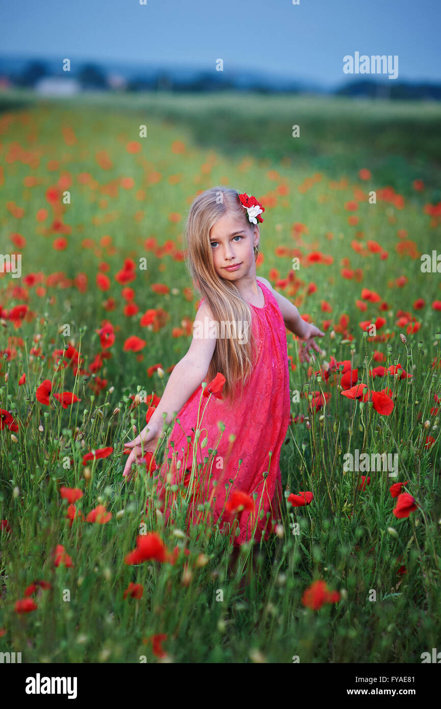 Bella ragazza in abito rosso passeggiate al campo di papavero Foto Stock