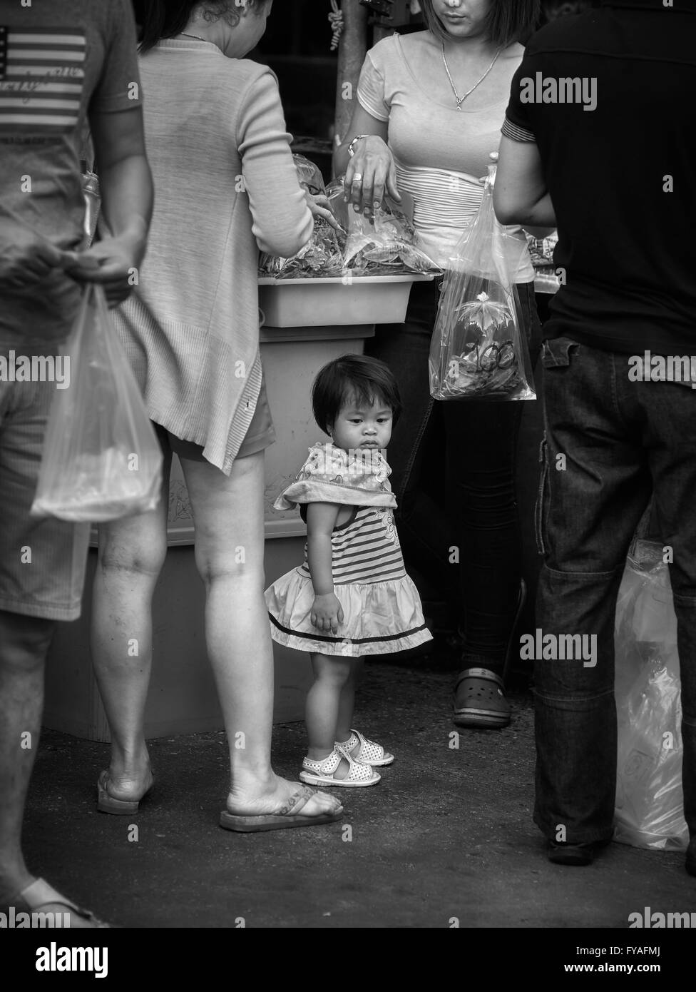 Piccolo bambino in un mondo cresciuto. Fotografia in bianco e nero Foto Stock