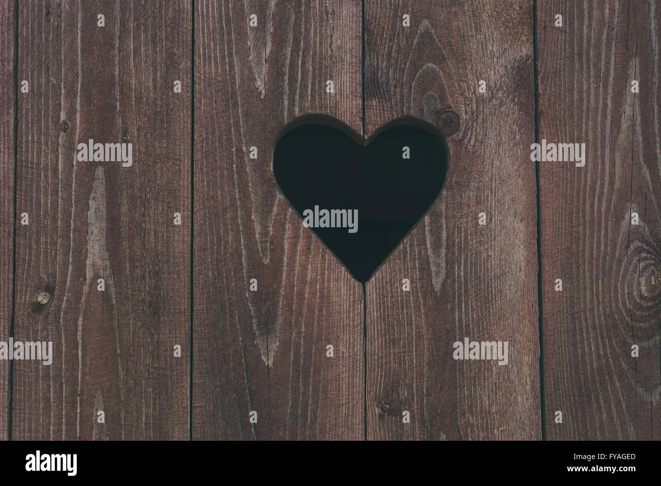 Il simbolo del cuore sulla toilette esterna porta in legno Foto Stock