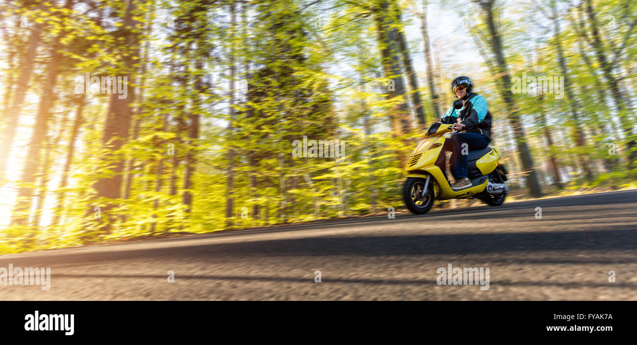 Giovane uomo alla guida di scooter e moto di sfocatura Foto Stock