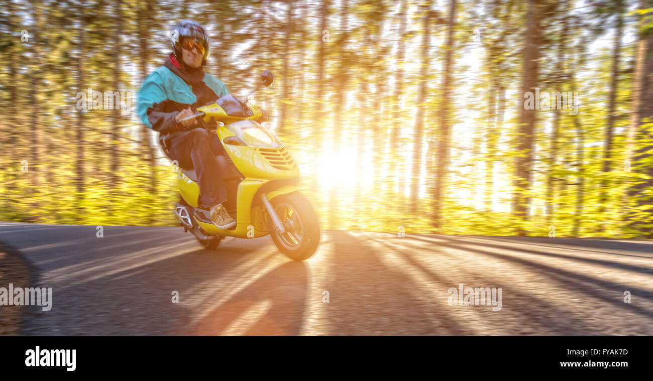 Giovane uomo alla guida di scooter e moto di sfocatura Foto Stock