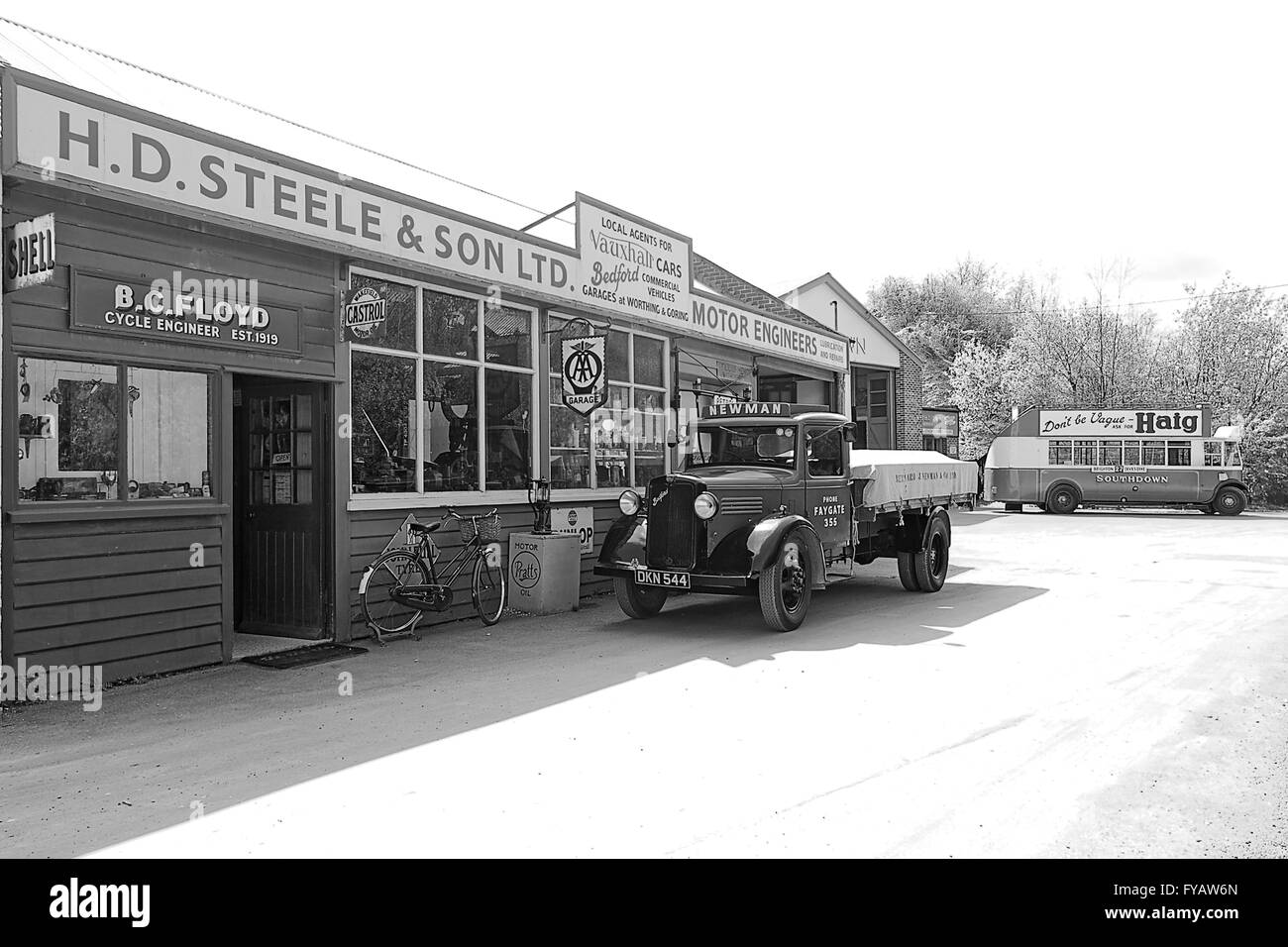 Monocromatico pre-guerra 1930 (1936/8) Commercial Bedford serie W a 2 Ton carrello al di fuori del centro storico garage con bus di Leyland in background Foto Stock