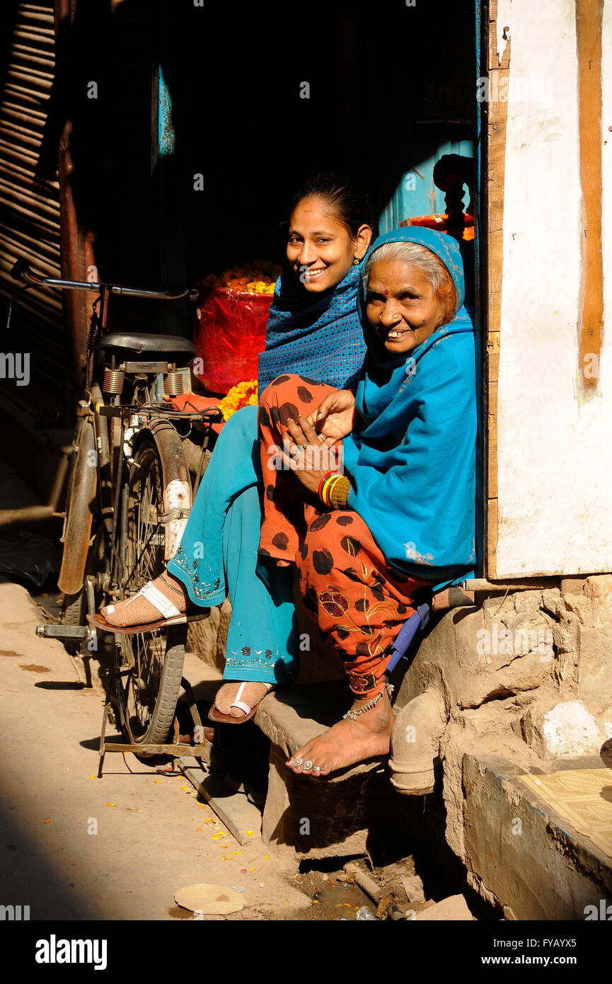 Indian la nonna e la nipote sedervi al sole sulla fase di fronte il loro piccolo negozio a Delhi Foto Stock