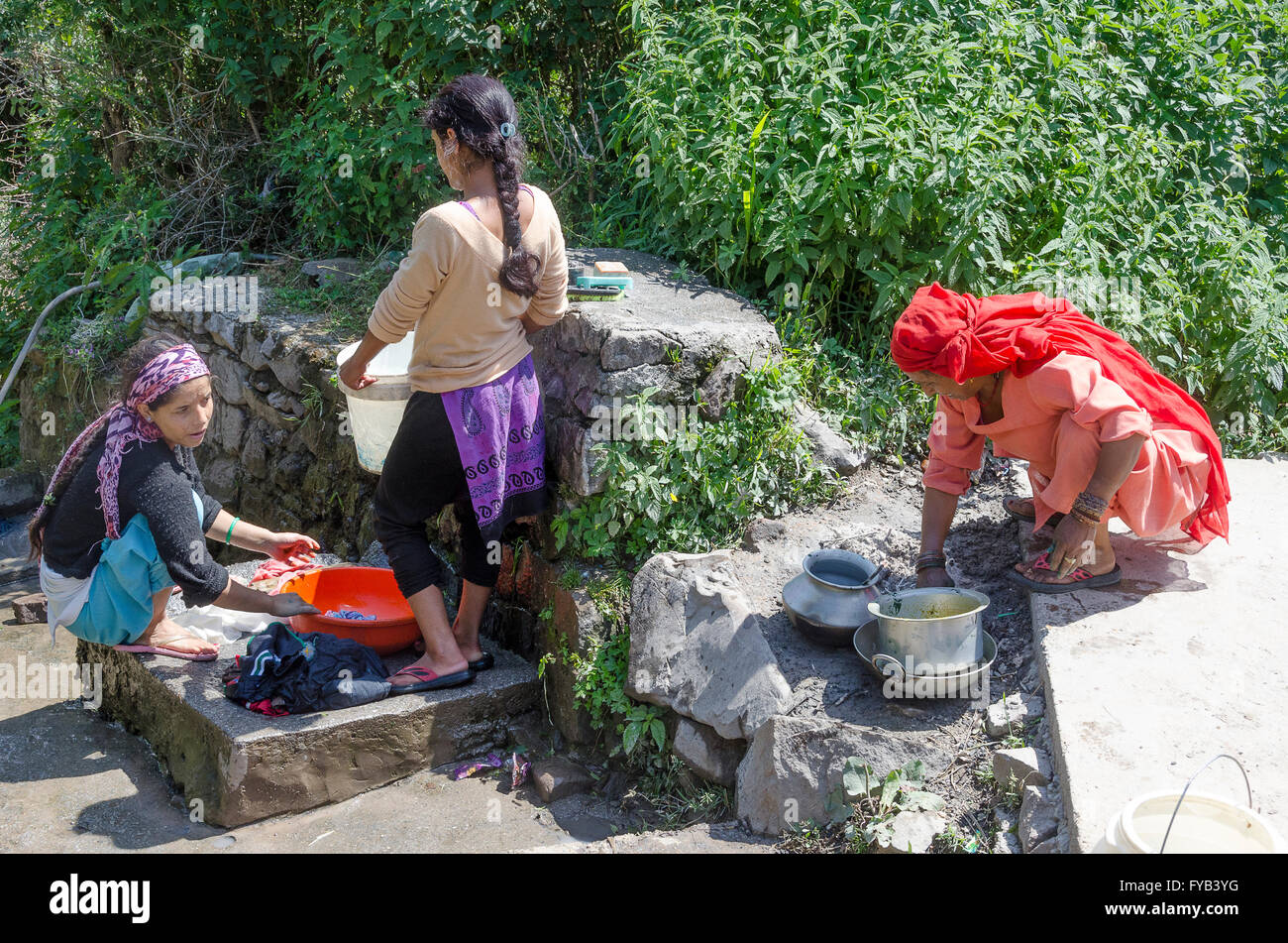 Tre donne a lavare i panni e stoviglie sul sentiero, villaggio nei pressi di McLeod Ganj, Dharamshala, Distict Kangra, Himachal Pradesh, in Foto Stock