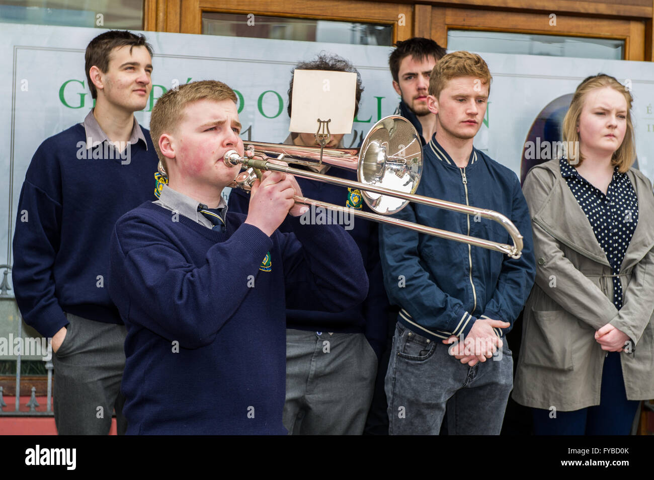 Skibbereen, Irlanda. 24 Aprile, 2016. Attuali ed ex alunni stand silenziosamente come Eoin Leahy riproduce gli ultimi post il trombone durante la misericordia altezze della scuola Annuncio evento della durata di un giorno per commemorare i 100 anni dall'inizio della ribellione in Dublino. Credito: Andy Gibson/Alamy Live News Foto Stock