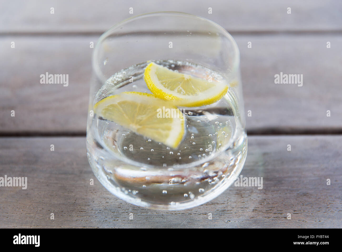 Bicchiere di acqua frizzante con limone sul tavolo Foto Stock