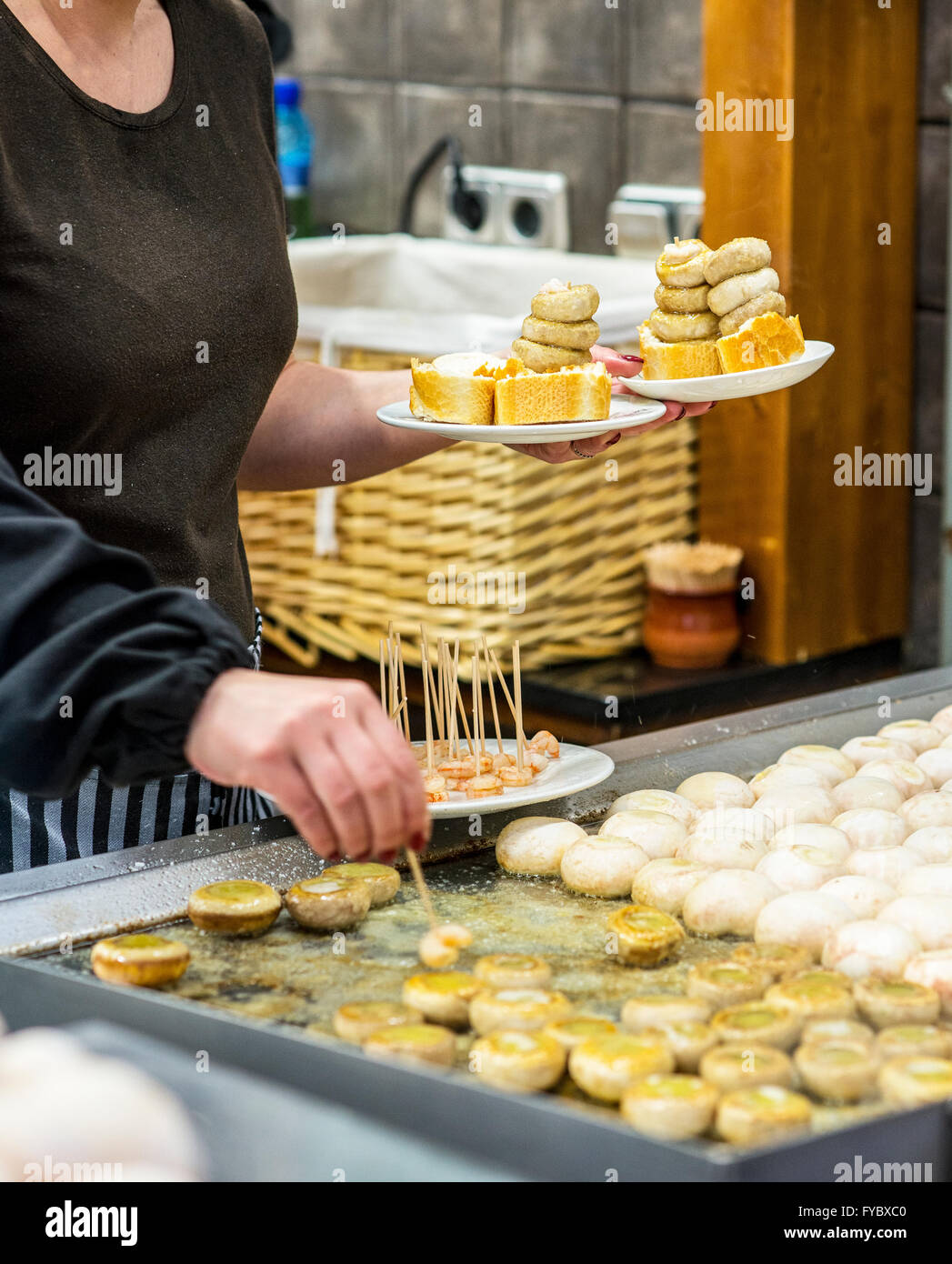 Cuocere la cottura di un tipico spagnolo di funghi pincho (Pintxo de champiñones) in una cucina. Foto Stock