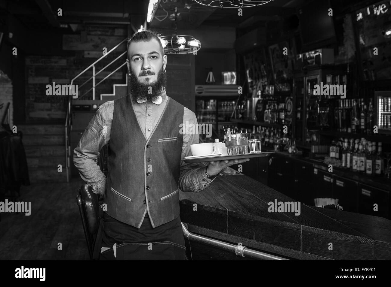 Bello il cameriere in un ristorante con vassoio. Bianco e nero modifica. Foto Stock