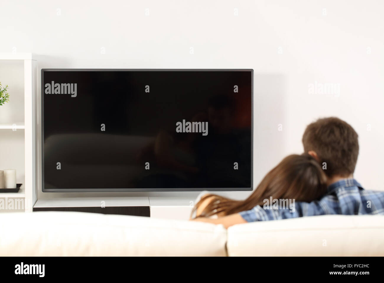 Vista posteriore di un paio di guardare la tv in un lettino a casa. Lo schermo è vuoto visualizza Foto Stock