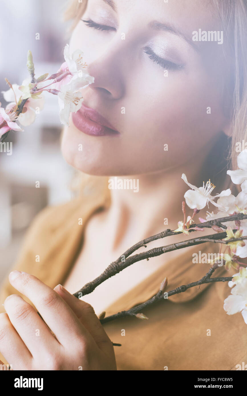 Bella giovane donna profumati fiori sulla struttura ad albero Foto Stock