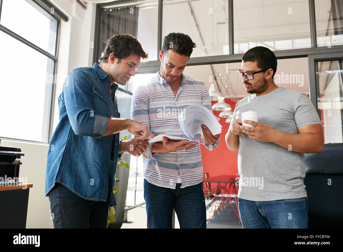Persone creative discutendo piani in un incontro permanente presso un ufficio moderno. Giovani designer maschio a discutere di nuovi disegni su carta wit Foto Stock