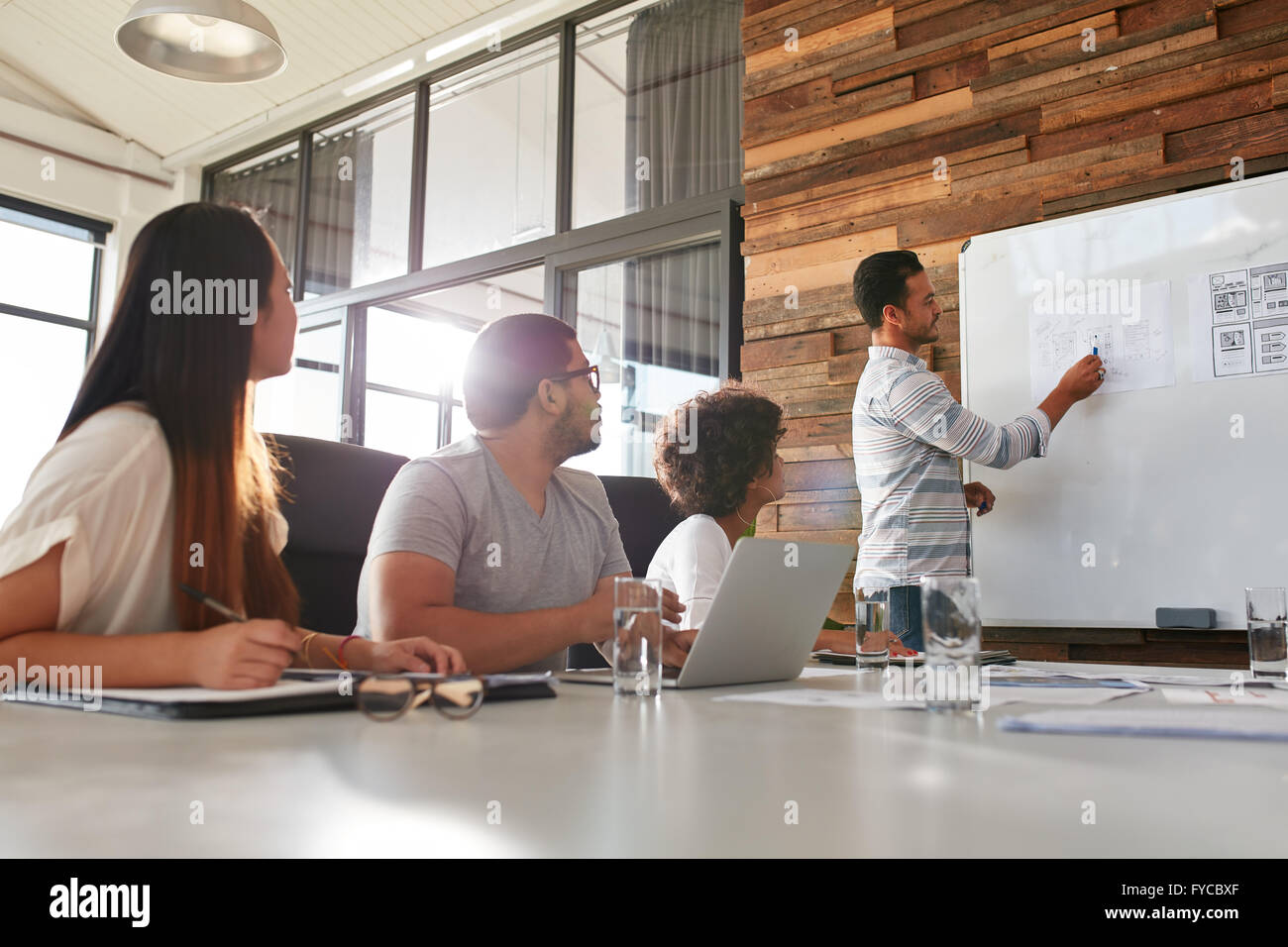 Colpo di un maschio di lavoratore di ufficio dando presentazione creativa ai suoi colleghi. Imprenditore spiegando business plan ai colleghi ho Foto Stock