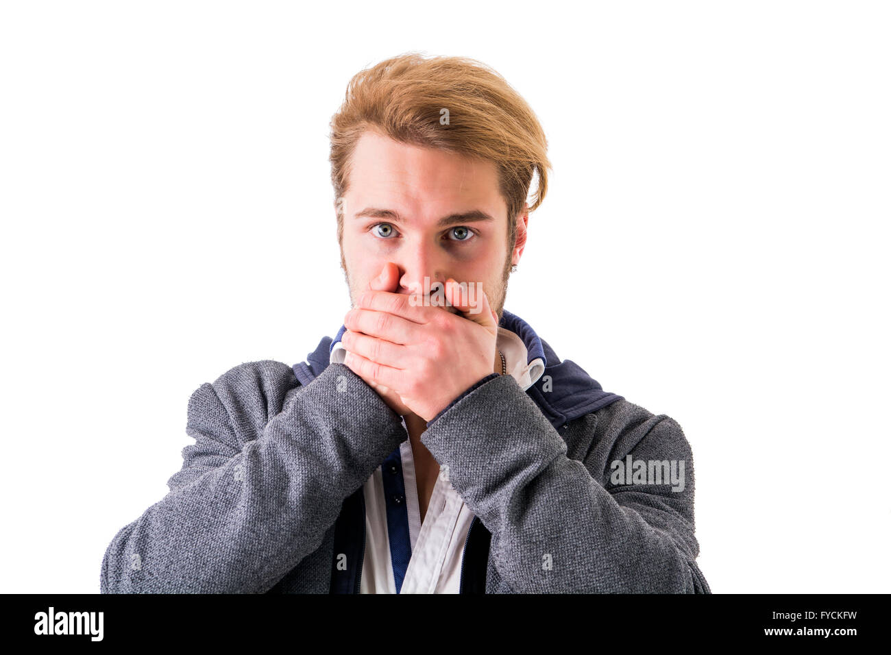 Bionda e giovane uomo che copre la sua bocca mentre guardando la telecamera contro di sfondo bianco Foto Stock