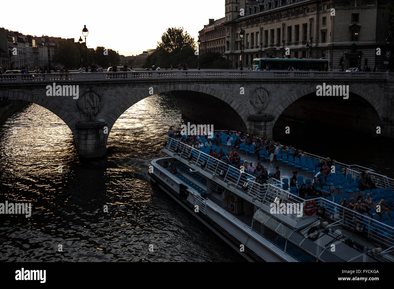 I membri del pubblico godendo del tramonto accanto al canale quando una barca di passare sotto il ponte a Parigi. La Francia. Pic pak@ Mera Foto Stock