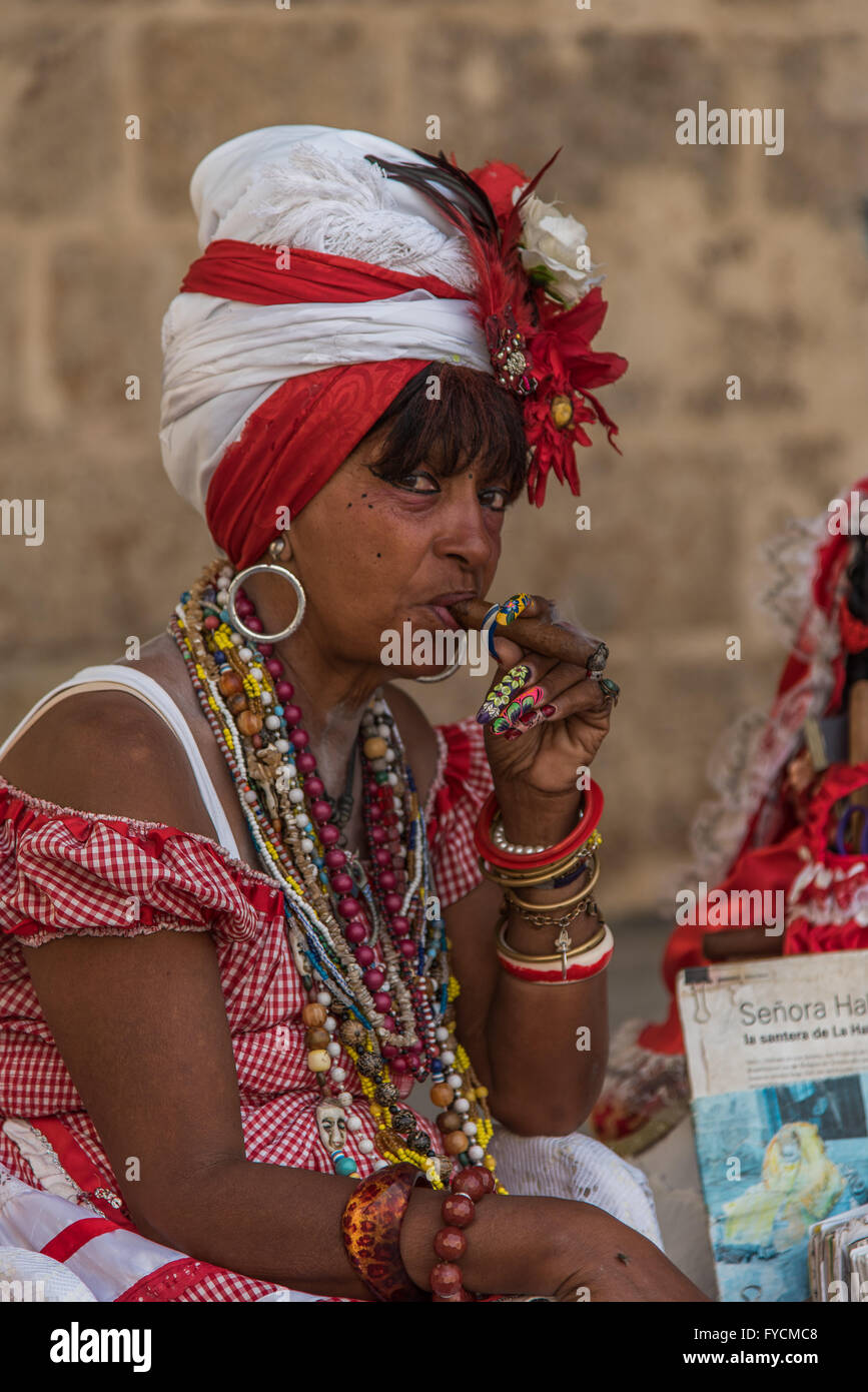 Una signora cubana vestita in costume tradizionale fuma un sigaro Foto Stock
