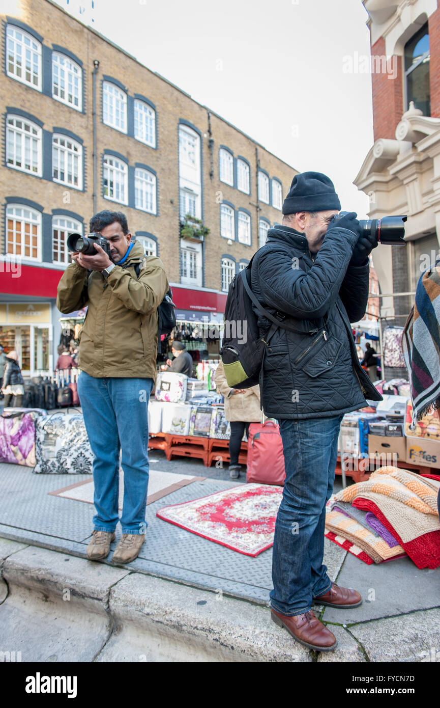 Due fotografi come parte di gruppo guidate a piedi attorno a Petticoat mercato nella zona est di Londra. Foto Stock