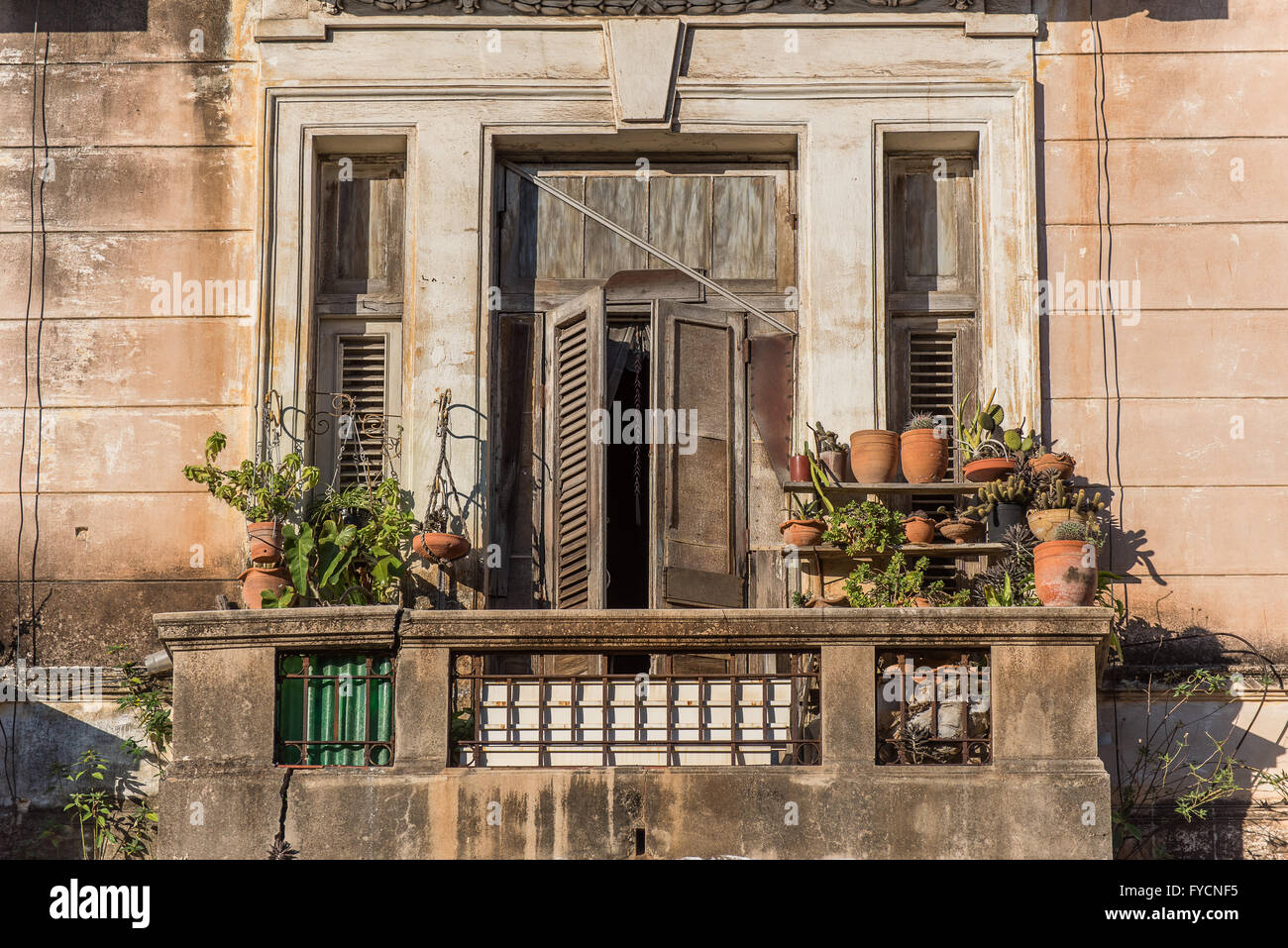 Finestra con persiane rustiche e balcone con pentole in terracotta. Bagnata dalla luce di prima sera. L'Avana, Cuba Foto Stock