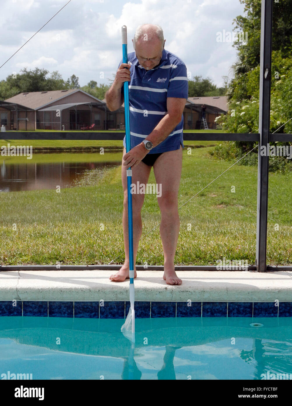 Uomo maturo facendo la manutenzione della piscina a sua florida piscina home, 25 aprile 2016 Foto Stock