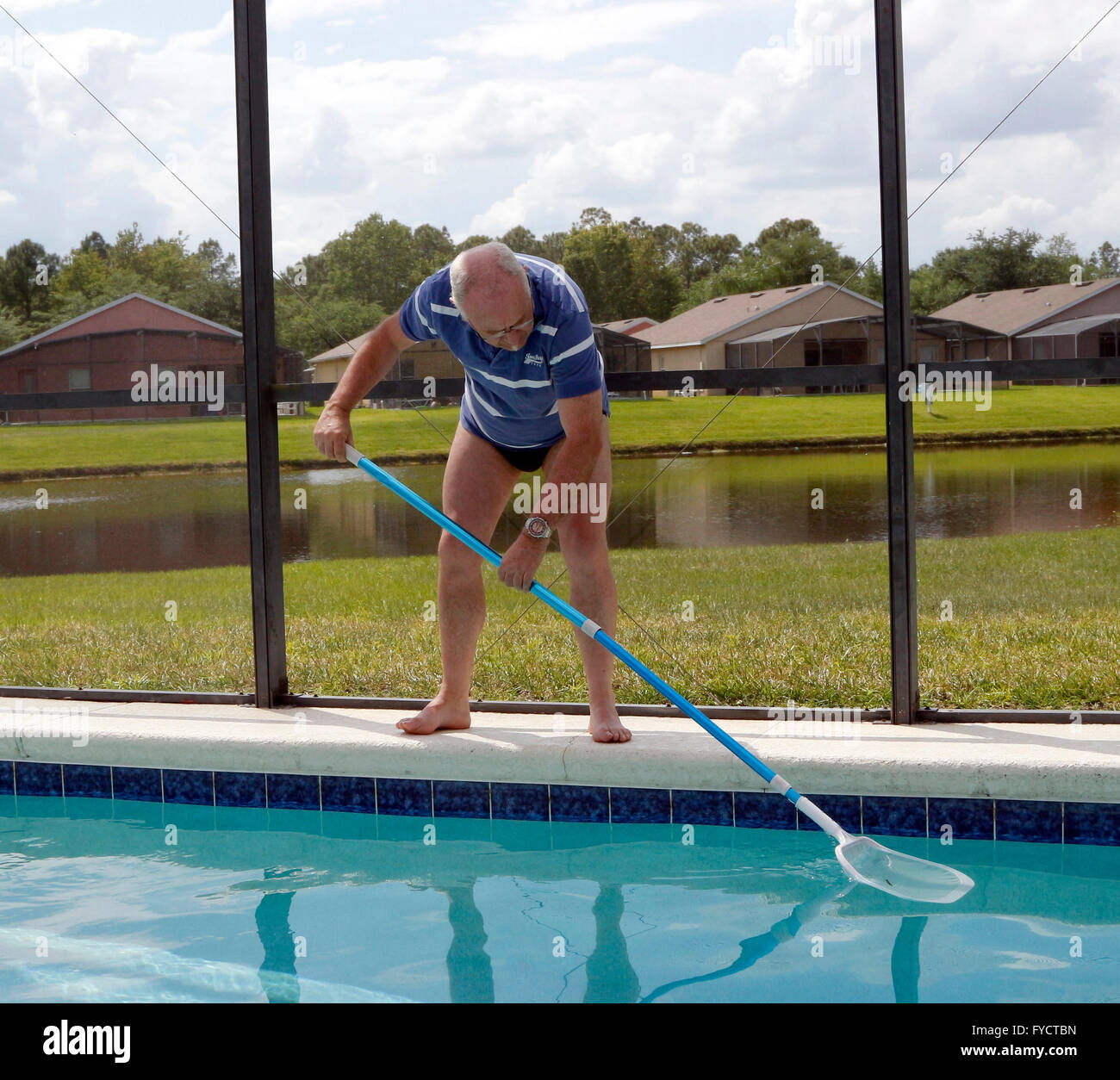 Uomo maturo facendo la manutenzione della piscina a sua florida piscina home, 25 aprile 2016 Foto Stock