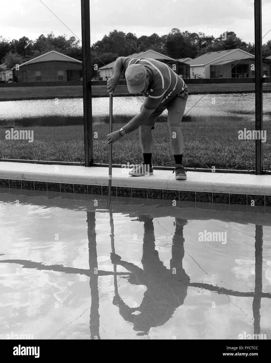 Uomo maturo facendo la manutenzione della piscina a sua florida piscina home, 25 aprile 2016 Foto Stock