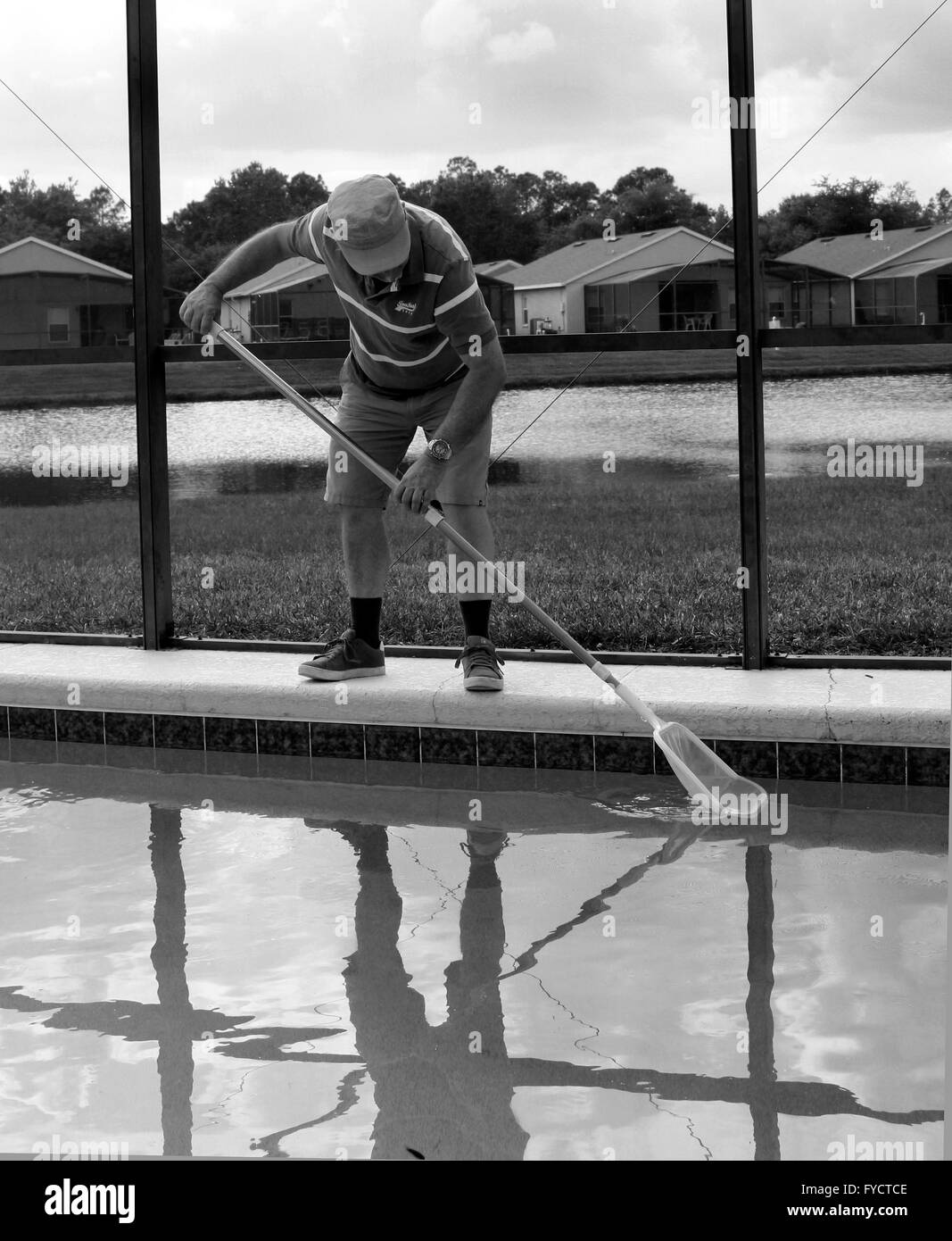 Uomo maturo facendo la manutenzione della piscina a sua florida piscina home, 25 aprile 2016 Foto Stock