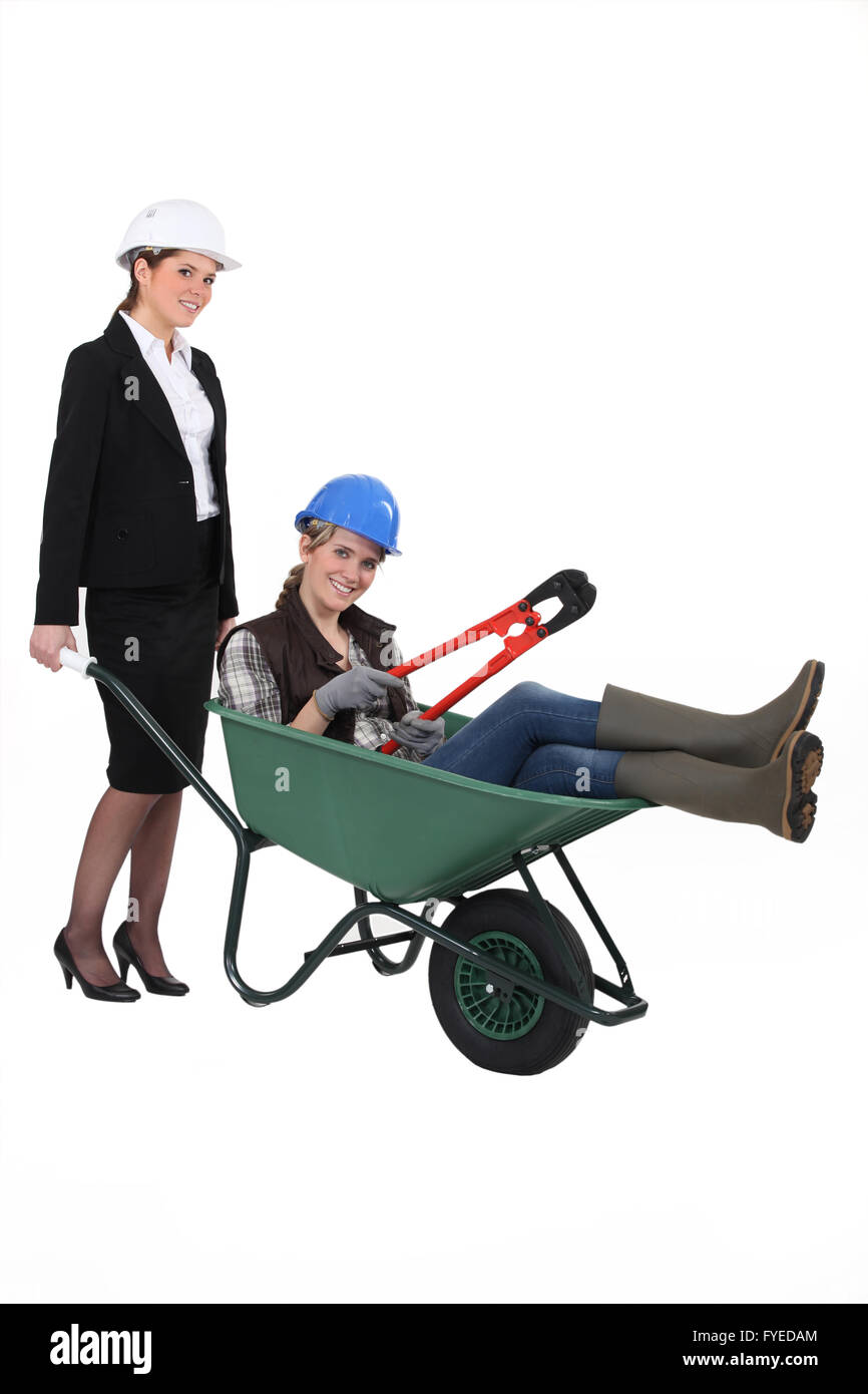 Un professionista di donna spingendo un collare blu lavoratore in una carriola Foto Stock