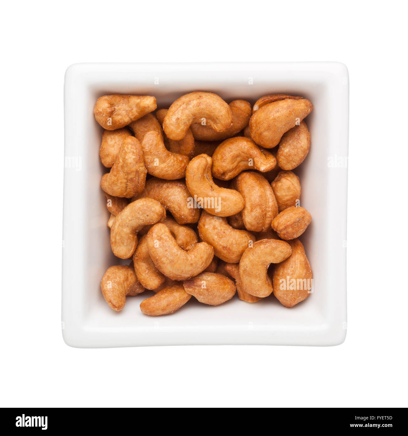Arrosto di noci di anacardio in un recipiente quadrato isolato su sfondo bianco Foto Stock