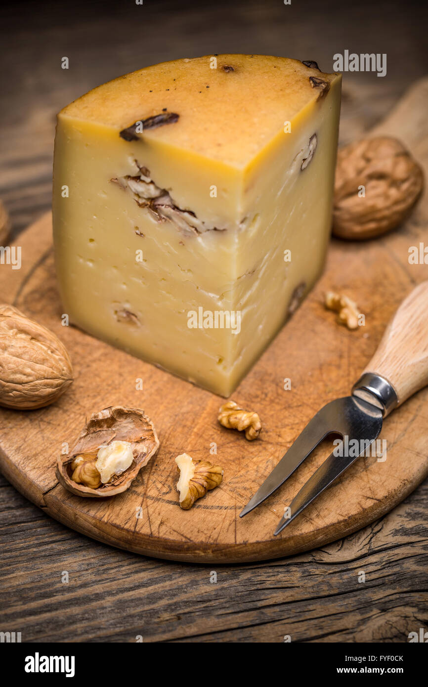 Pezzo di formaggio artigianale con noci sul pannello di legno Foto Stock