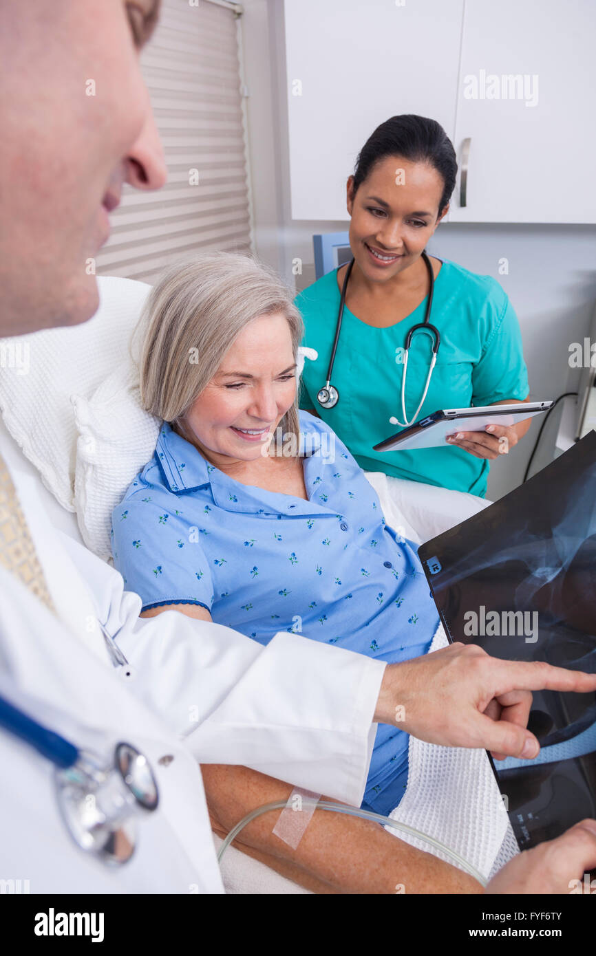 Un felice senior donna femmina paziente anziano a letto guardando a raggi X di un'anca con connettore maschio di tipo medico e infermiere ispanica Foto Stock