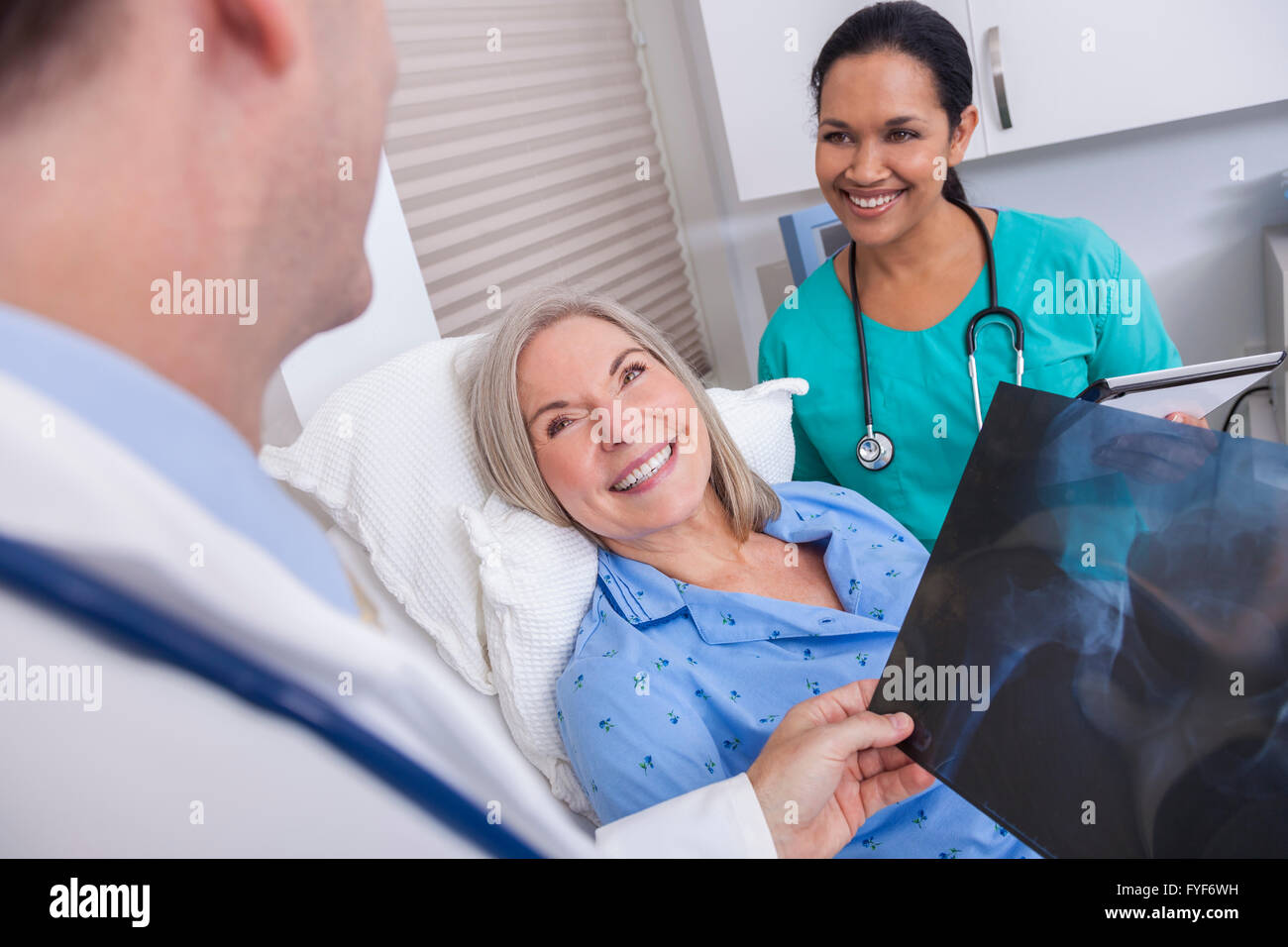 Un felice senior donna femmina paziente anziano a letto guardando a raggi X con connettore maschio di tipo medico e infermiere ispanica Foto Stock