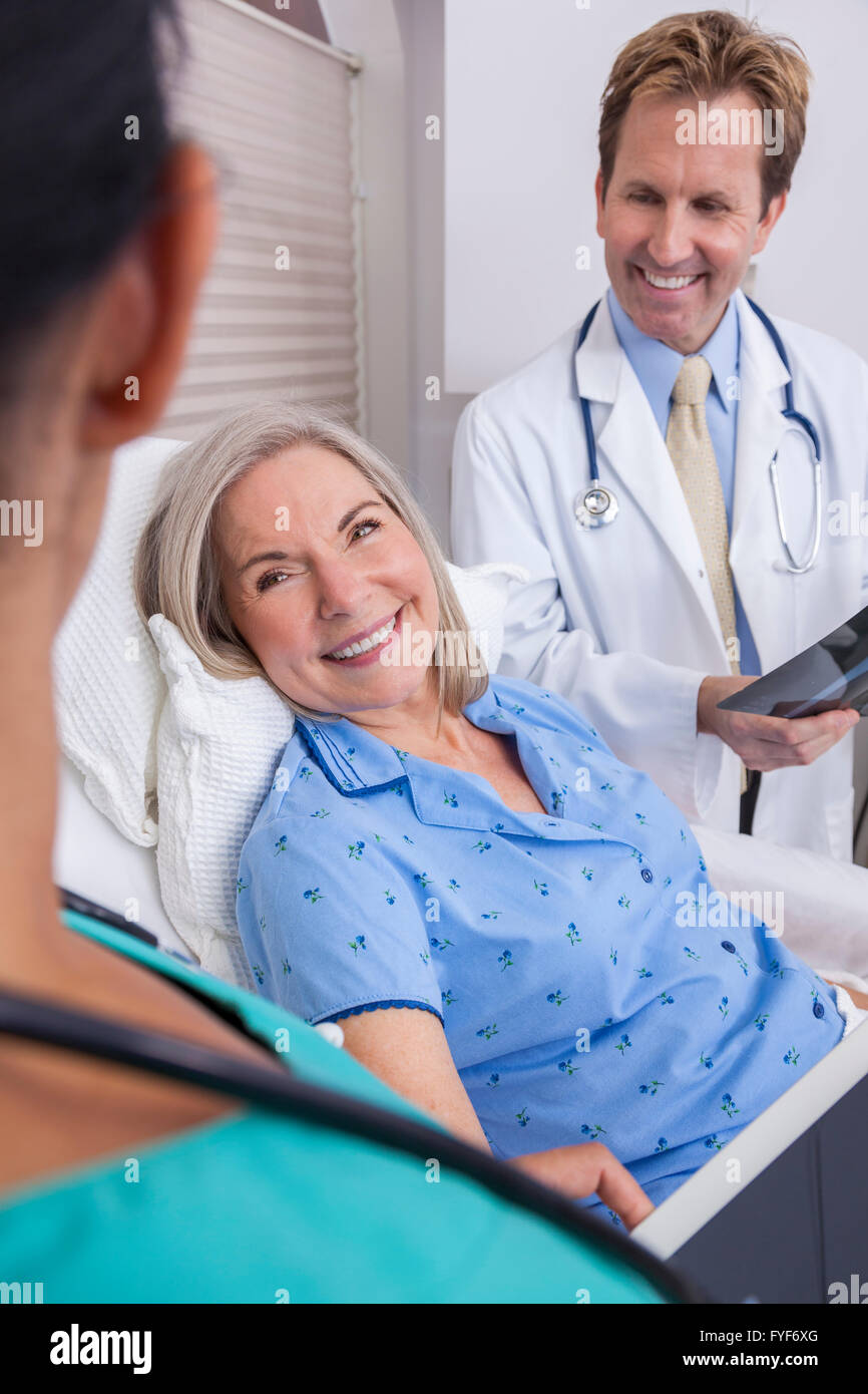 Un felice senior donna femmina paziente anziano a letto guardando a raggi X con connettore maschio di tipo medico e infermiere ispanica Foto Stock